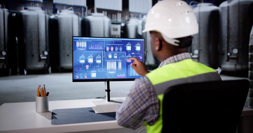 warehouse worker focusing on tank liquid measurements on screen